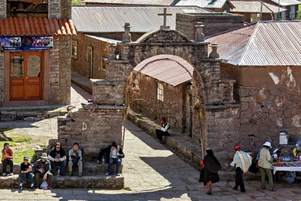A bustling marketplace in a traditional village with stone walls and arches, The city's large square on Taquile Island in Lake Titicaca in Peru