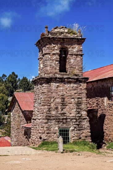 An old stone church with a bell tower and red roofs under a blue sky, The historic church on Taquile Island in Lake Titicaca in Peru