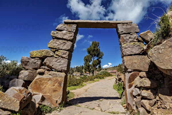 Rectangular stone archway with visible path below, blue sky in the background, stone gates on Taquile Island in Lake Titicaca in Peru