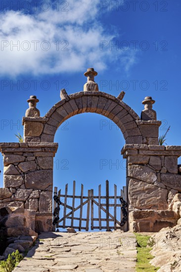 Stone gate under blue sky with some clouds, rustic appearance, stone gates on the island of Taquile in Lake Titicaca in Peru