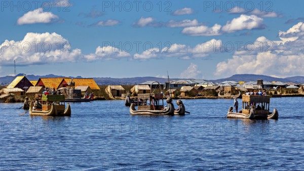 Several boats near a collection of reed huts on the lake, The floating reed islands of the Uros in Lake Titicaca in Peru