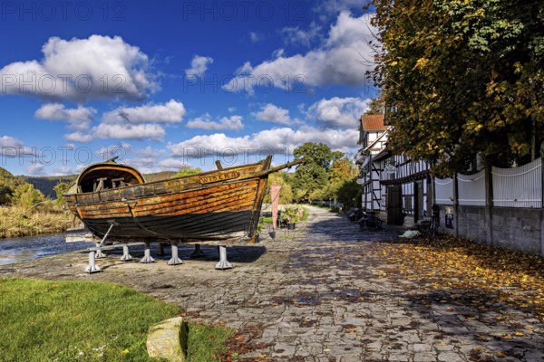 Rustic wooden boat on supports on a paved road next to a half-timbered house in autumn, the port of Wanfried an der Werra with the historic Werra ship