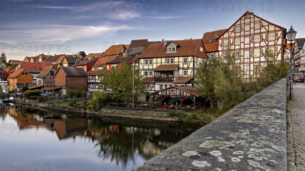 Historic half-timbered houses and beer garden along a river with a bridge at dusk, The town of Bad Sooden Allendorf an der Werra in the Werra Meissner district of Hesse