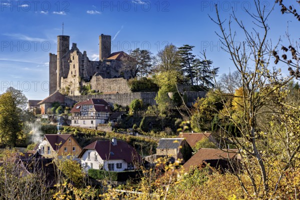 Medieval castle above a village with autumn trees under a blue sky, Hanstein Castle near Bornhagen in the Eichsfeld district of Thuringia
