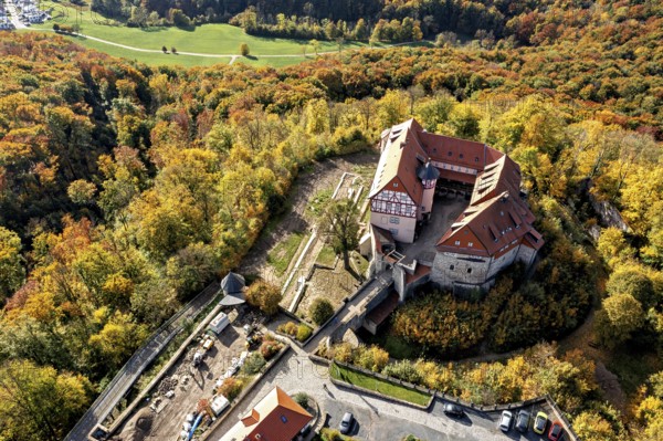 Castle with red tiled roofs, surrounded by autumn-coloured forest landscape, from a bird's eye view, Bodenstein Castle in the Eichsfeld district of Thuringia