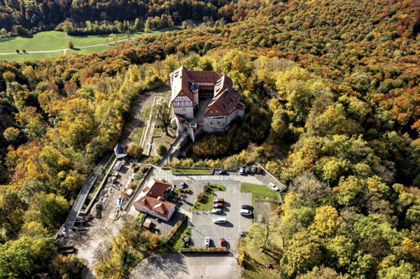 Castle taken from the air in the midst of autumn nature, with adjacent parking facilities, Bodenstein Castle in the Eichsfeld district of Thuringia
