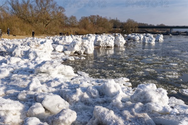 Many visitors look at the icebergs on the water of the Elbe and on the banks of the Elbe Island near Geesthacht on a cold winter day. Geesthacht, Schleswig-Holstein, Germany