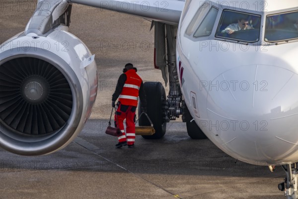 Ground crew positions brake blocks on the chassis, after stopping at the parking position, at the terminal, gate, at the Cologne/Bonn airport passenger bridge, CGN, North Rhine-Westphalia, Germany