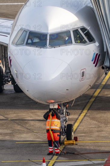 Ground crew installs ground power, power supply for the aircraft after stopping at the parking position, at the terminal, gate, at the Cologne/Bonn airport passenger bridge, CGN, North Rhine-Westphalia, Germany