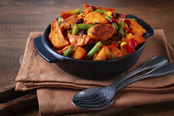 Steakhouse pfanne, fried potato slices, with meatballs, and vegetable mixture, on a black plate