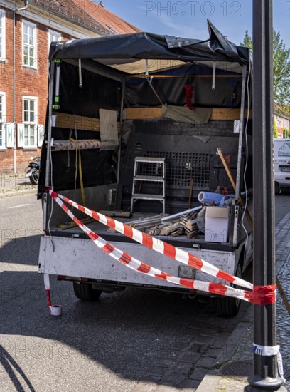 Red and white barrier tape in front of the back of a pickup truck, Potsdam, Brandenburg, Germany