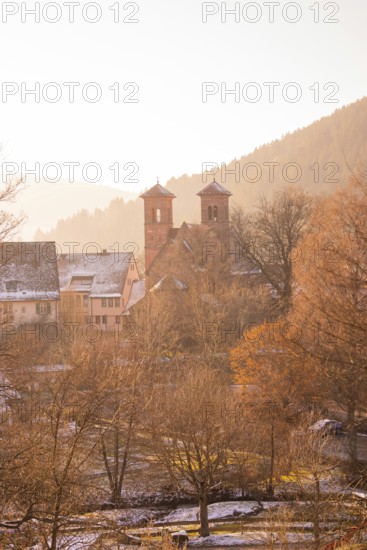 Idyllic snowy village with church towers and mountains in the background, Black Forest, Germany