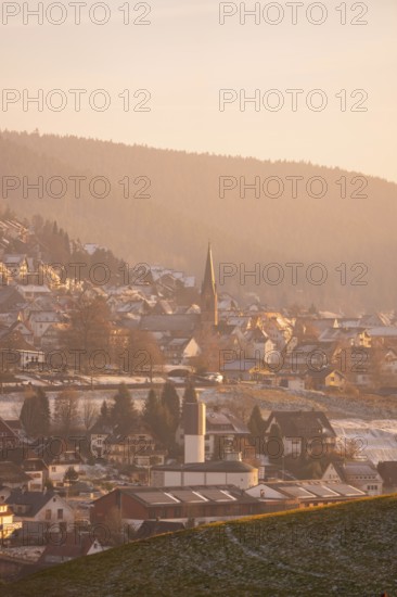 Snowy village with church and houses in a hilly area, Black Forest, Germany