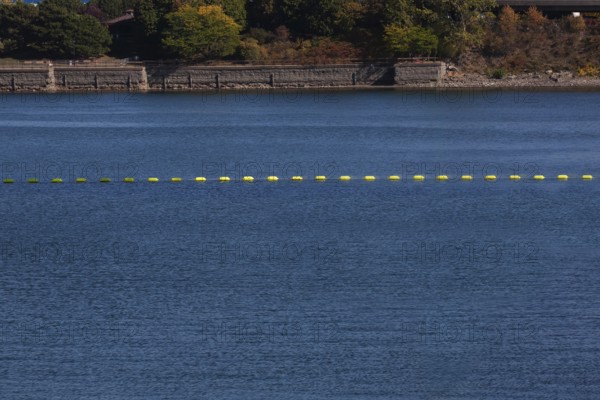 String of yellow cautionary navigation marker buoys on water surafce of river serving to warn, signal or indicate of a hazard beyond, Old Port of Montreal, Quebec, Canada