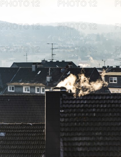 Smoke plume from a chimney over densely built residential area in the evening light, wintry city scene, Wuppertal, Germany