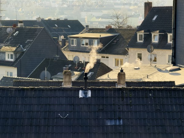 Smoke plume from a chimney over densely built residential area in the evening light, wintry city scene, Wuppertal, Germany
