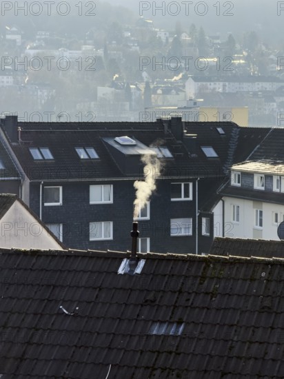 Smoke plume from a chimney over densely built residential area in the evening light, wintry city scene, Wuppertal, Germany
