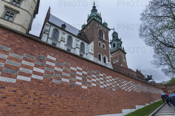 North façade of the cathedral on Wavelhügel, tourist group in the rain, Krakow, Poland