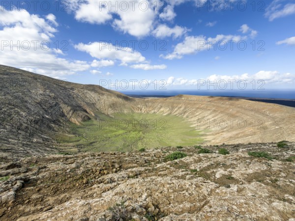 View of the Caldera Blanca volcano cauldron against blue sky with white clouds, Mancha Blanca, Lanzarote, Canary Islands, Spain