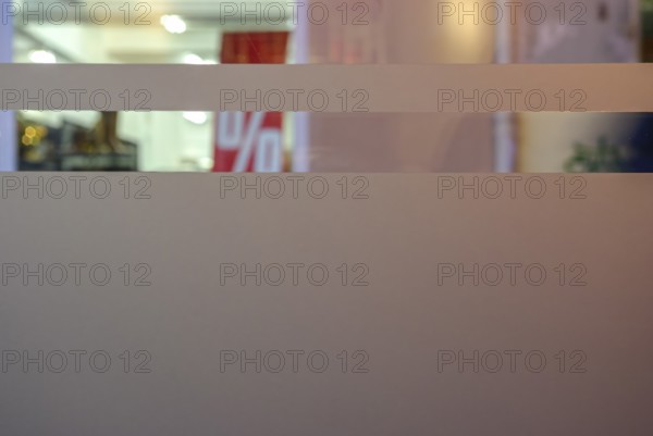 Symbolic picture of final sale: A percentage sign visible through the shop windows of a retail store indicates the sale, sale or general discount campaign