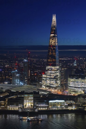The Shard, pyramid-shaped skyscraper and London Bridge Station along the River Thames in Southwark at night at the capital city London, England, UK