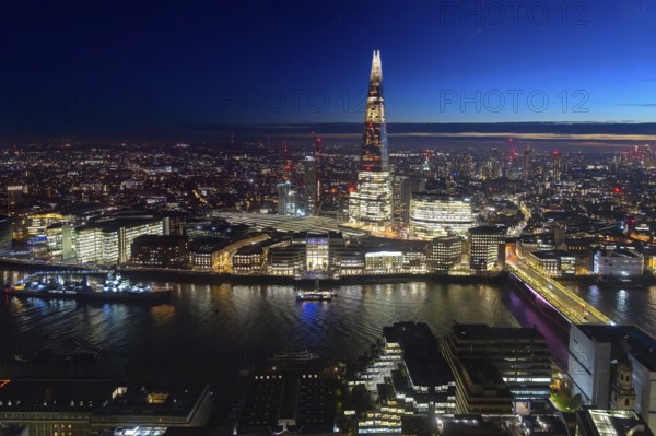 The Shard, pyramid-shaped skyscraper and London Bridge Station along the River Thames in Southwark at night at the capital city London, England, UK