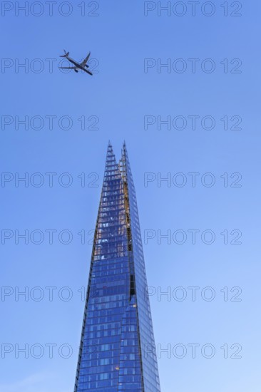 Airplane of British Airways flying over The Shard, skyscraper and tallest building in the United Kingdom in Southwark in the city London, England, UK
