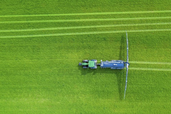Aerial view over tractor towed liquid manure spreader, slurry spreader enabling the fertilization of arable land by distributing slurry in spring