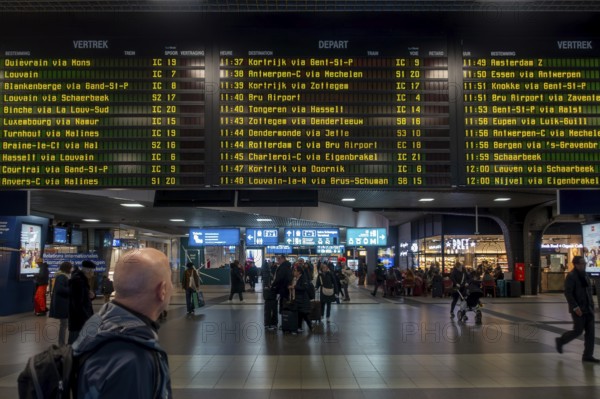 Commuter, tourist looking at train departures in departure hall of the NMBS Brussels-South railway station, Gare de Bruxelles-Midi, Belgium
