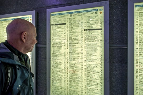 Traveler, commuter looking at train departures in timetable of NMBS Brussels-South railway station, Gare de Bruxelles-Midi in Brussels, Belgium. Model released