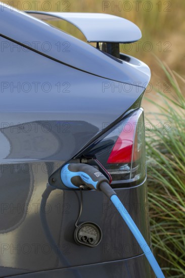 Close-up of electric vehicle / EV recharging at public charging station / loading point for electric cars showing cable, connector and vehicle inlet