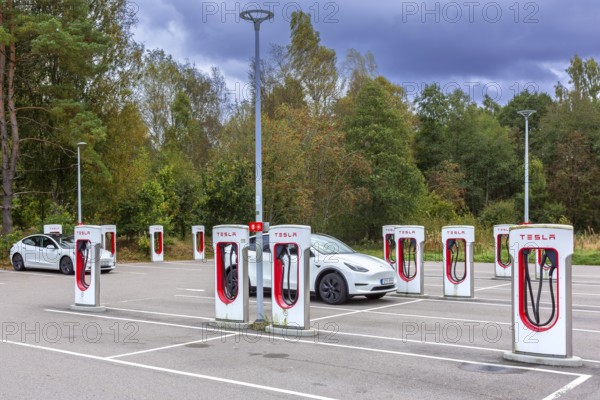 Parking area with public charging station / loading points from Tesla, network of rapid chargers for electric vehicles / cars in Sweden