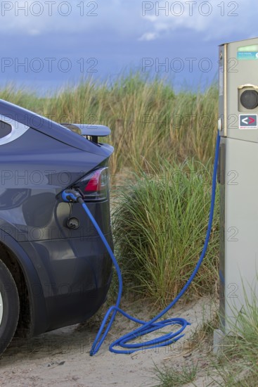Electric vehicle / EV charging at public charging station / loading point for electric cars in the dunes on the island Texel, Netherlands