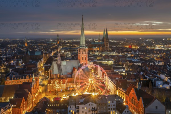 St. James' Church / Jakobikirche and illuminated Ferris wheel at evening Christmas market in winter at Koberg, Hanseatic city Lübeck, Germany