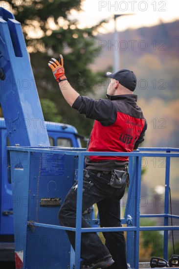 Man in red jacket standing on a blue lift, tree work, Gechingen, Calw district, Germany