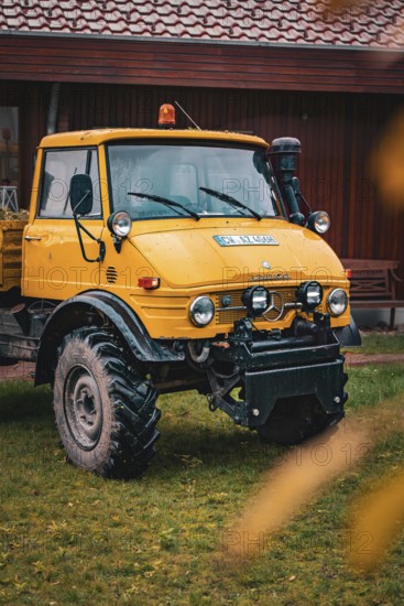A yellow Unimog stands in the rain on a farm, tree work, Gechingen, Calw district, Germany