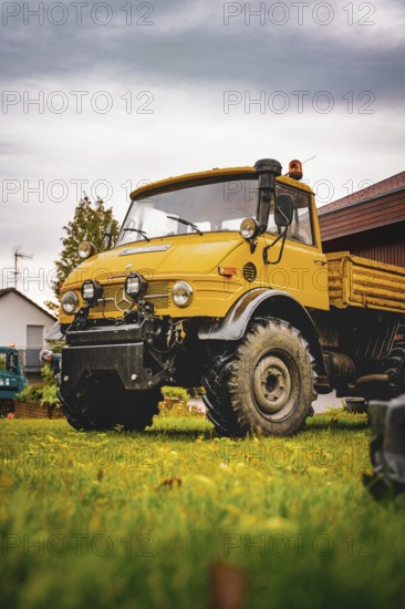 A yellow Unimog stands on a lawn under cloudy sky, tree work, Gechingen, Calw district, Germany