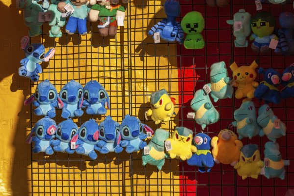 Close-up of blue, yellow and green plush prize dolls at game kiosk at Fun Show traveling ride park, Old Port of Montreal, Quebec, Canada