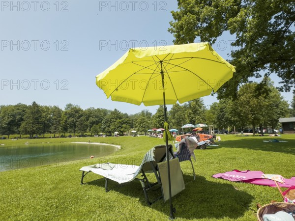 Vacation, umbrellas and sunbeds on the shores of Lake Neubeurer, Bavaria, Germany