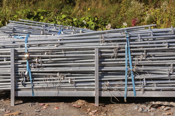 Pile of stacked heavy duty galvanized steel poles in outdoor storage yard in early autumn, Quebec, Canada