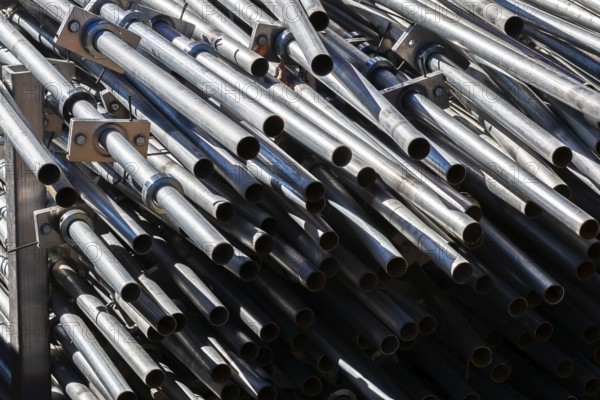 Close-up of stacked heavy duty galvanized steel poles in outdoor storage yard in early autumn, Quebec, Canada