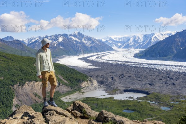 Young man enjoying the view, view of impressive mountain landscape with Matanuska glacier and glaciated mountain peaks, Lion's Head, Chugach Mountains, Alaska