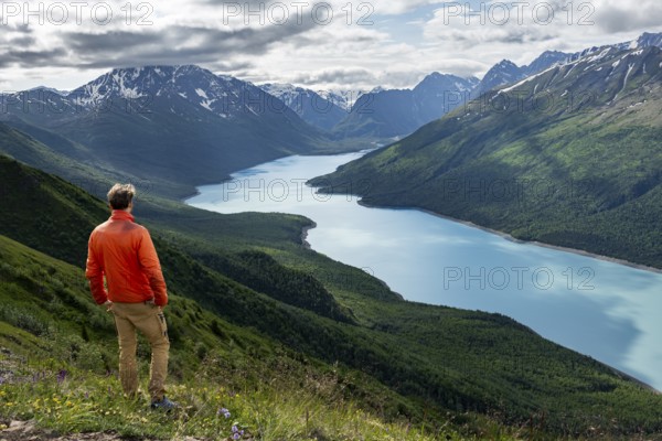 Mountaineer enjoys views of blue lake and mountains on Twin Peaks Trail, Eklutna Lake, Chugach Mountains, Chugach State Park, Alaska, USA