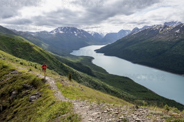 Climbers on a hiking trail, view of blue lake and mountains on Twin Peaks Trail, Eklutna Lake, Chugach Mountains, Chugach State Park, Alaska, USA