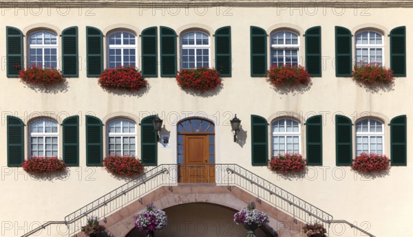 Architectural façade with symmetrical windows and green shutters decorated with red flowers, Bad Bergzabern Castle, Palatinate, Rhineland-Palatinate, Germany