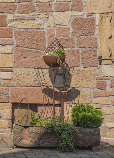 Rustic iron decoration on a stone wall, clay pot with plants in sunshine, Palatinate, Rhineland-Palatinate, Germany