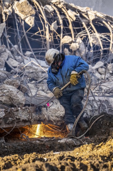 Workers with cutting torches demolishing the 120-meter long motorway bridge of the A516, across Teutoburger Straße in Oberhausen-Sterkrade, the bridge, built in 1970 was severely damaged, traffic continues to roll on the remaining west bridge, after demolition, the eastern part is rebuilt using a process that is unique in the world to date, 40 meter long precast concrete beams are assembled one after the other, reducing construction time from 24 to 7 months, After the completion of this bridge, the western part will also be rebuilt, North Rhine-Westphalia, germany