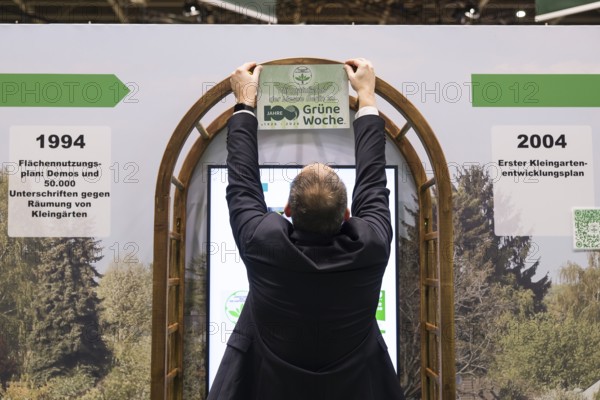 A stand operator hangs up a sign Congratulations to Messe Berlin on 100 years of Green Week at the exhibition center in Berlin on 16.01.2026. The Agricultural and Food Industry Fair will take place from January 16-25, 2026