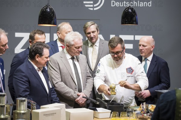 Christoph Minhoff (Managing Director of the Federation of German Food and Drink Industries), Alios Rainer (Federal Minister of Agriculture, Food and Home Affairs) and Kai Wegner (Governing Mayor of Berlin) preparing a currywurst from a one-person pack during the opening tour of the Green Week at the exhibition grounds in Berlin on 16 January 2026. The trade fair for the agricultural and food industry will take place from 16 to 25 January 2026