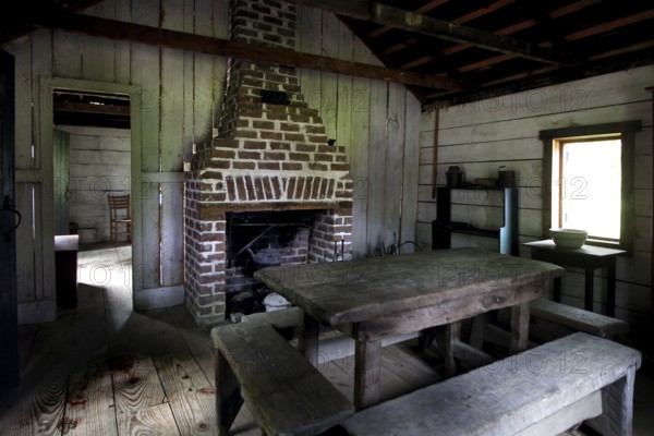Rustic interior decor of a slave shelter with fireplace and table, Charleston, South Carolina, USA